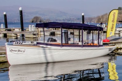 White boat with blue canopy docked at a marina with hire boats sign.